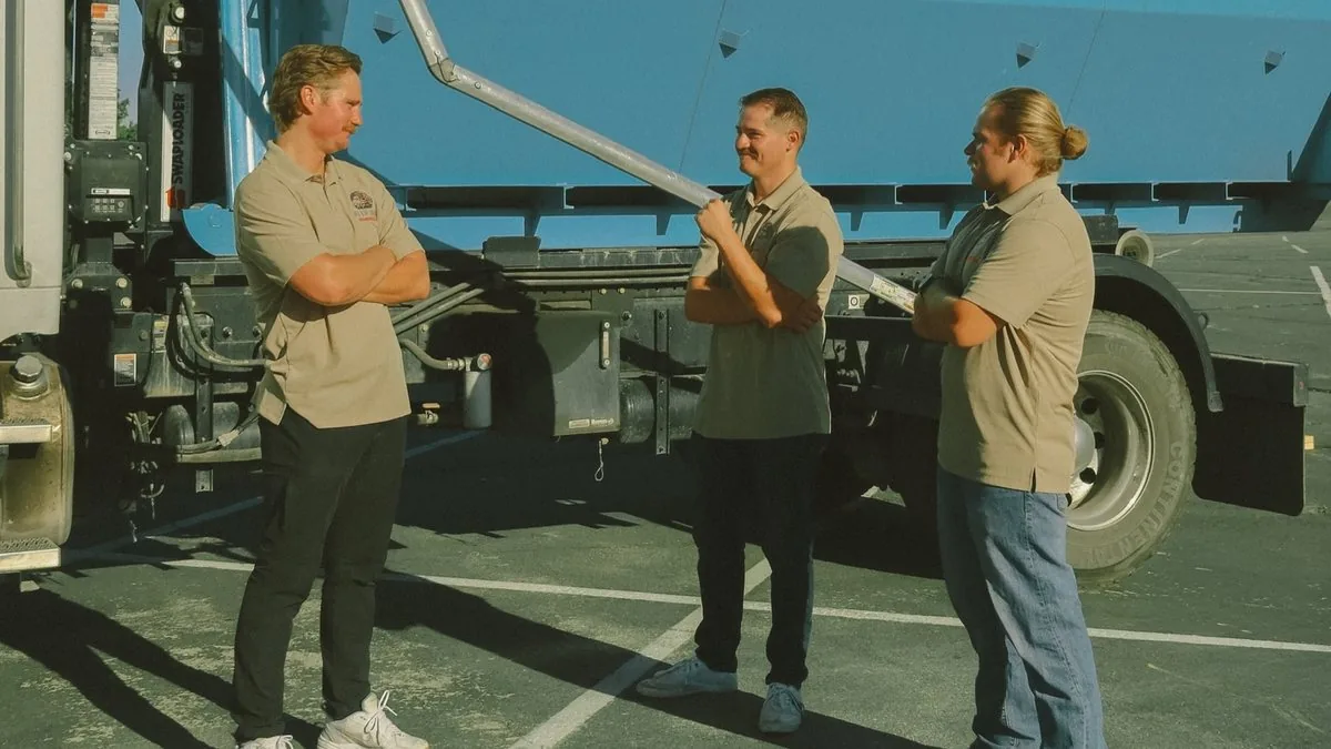 The Blue Bin crew talking beside their roll-off truck